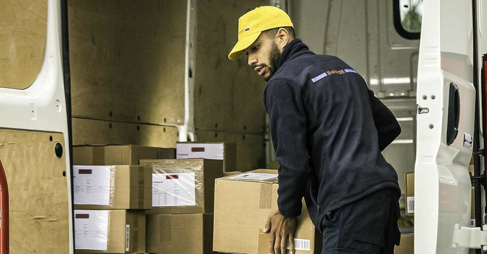 Gestão de transporte de cargas: homem descarregando veículo cheio de caixas